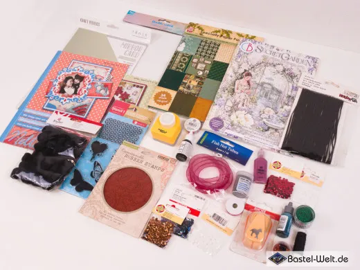 Vollständige Übersicht des 2.-Wahl-Sets 102 mit Ciao-Bella-Junk-Journal „Secret Garden“, weihnachtlichem Spezialpapier-Pack, schwarzen Kautschukstempeln und weiterem Scrapbooking-Zubehör.